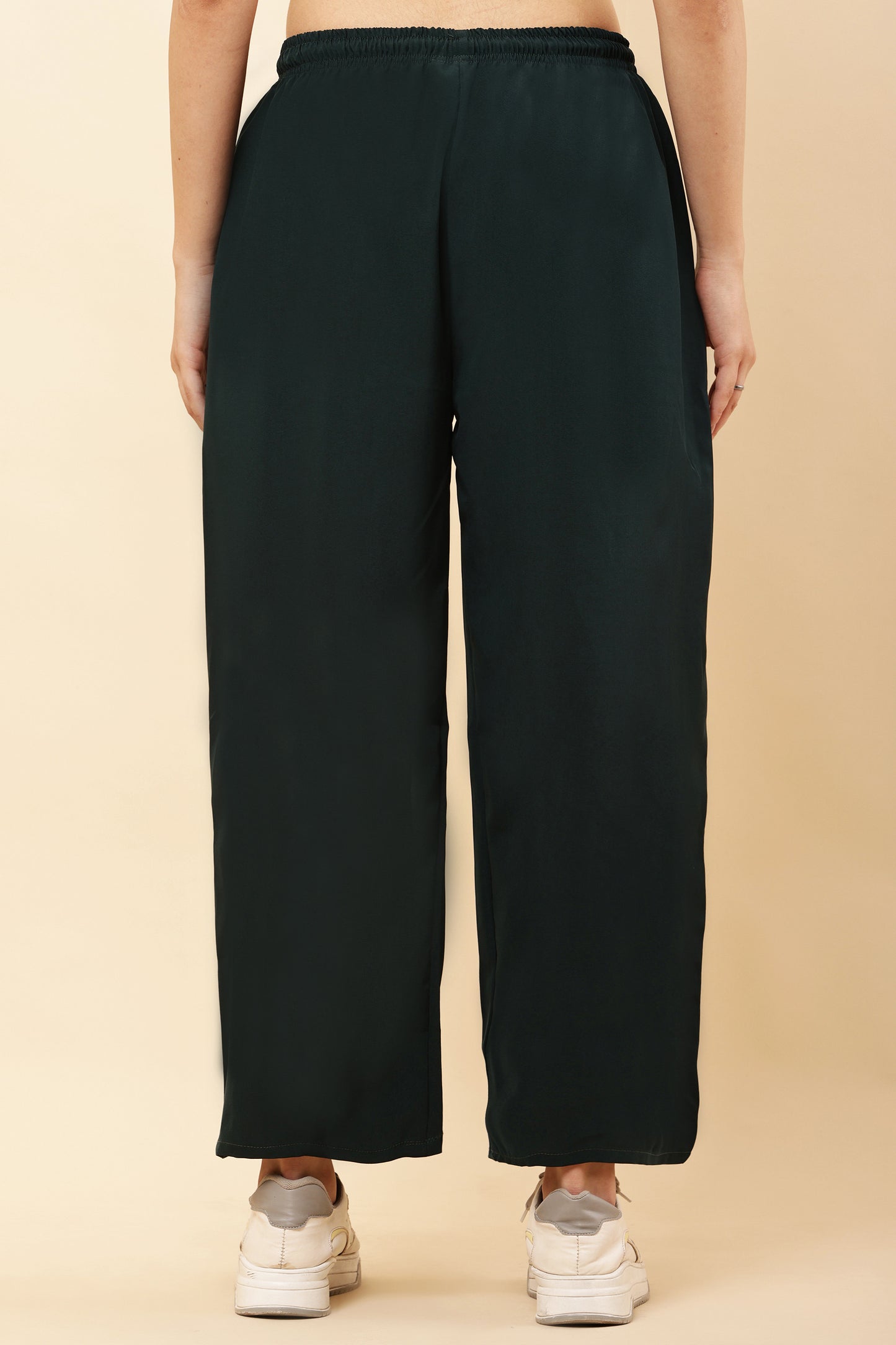 Person wearing black wide-leg pants on a beige background